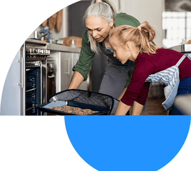 grandmother baking cookies in the oven with her granddaughter
